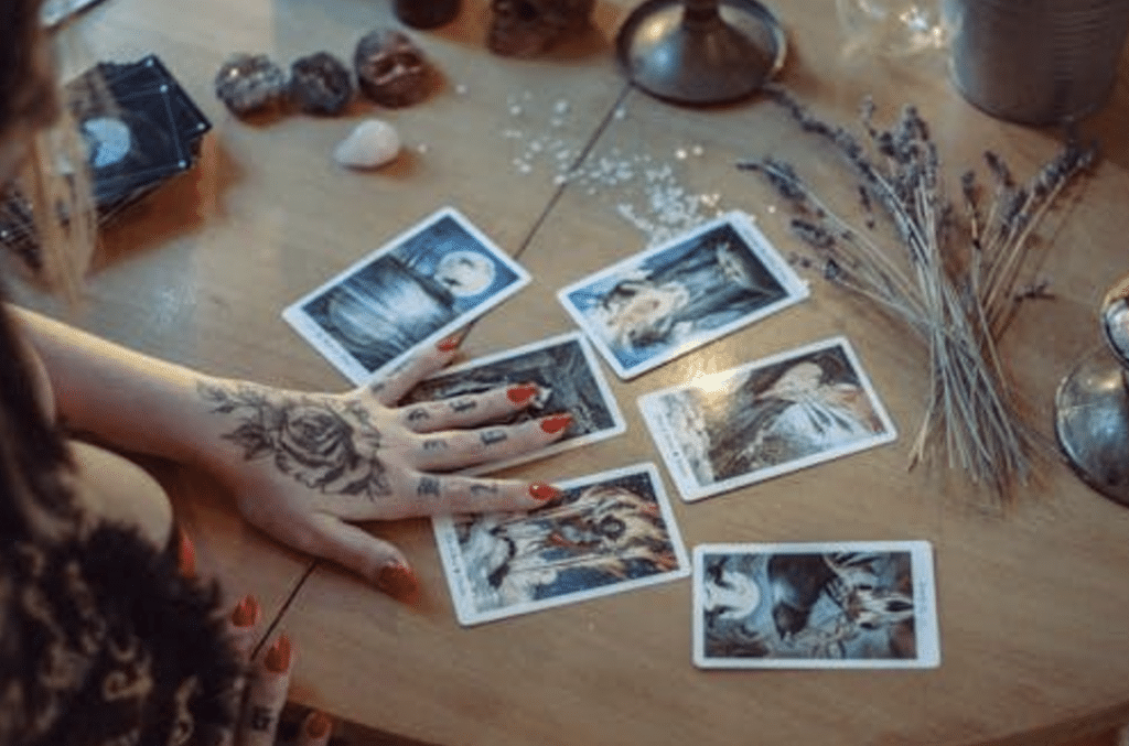 Una imagen de la mano de una adivina con cartas del Tarot sobre la mesa.